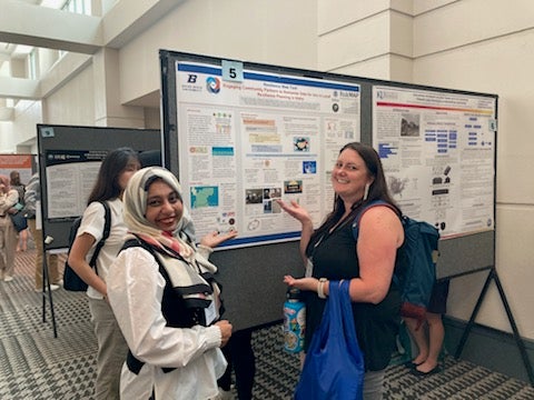 Graduate students presenting research poster