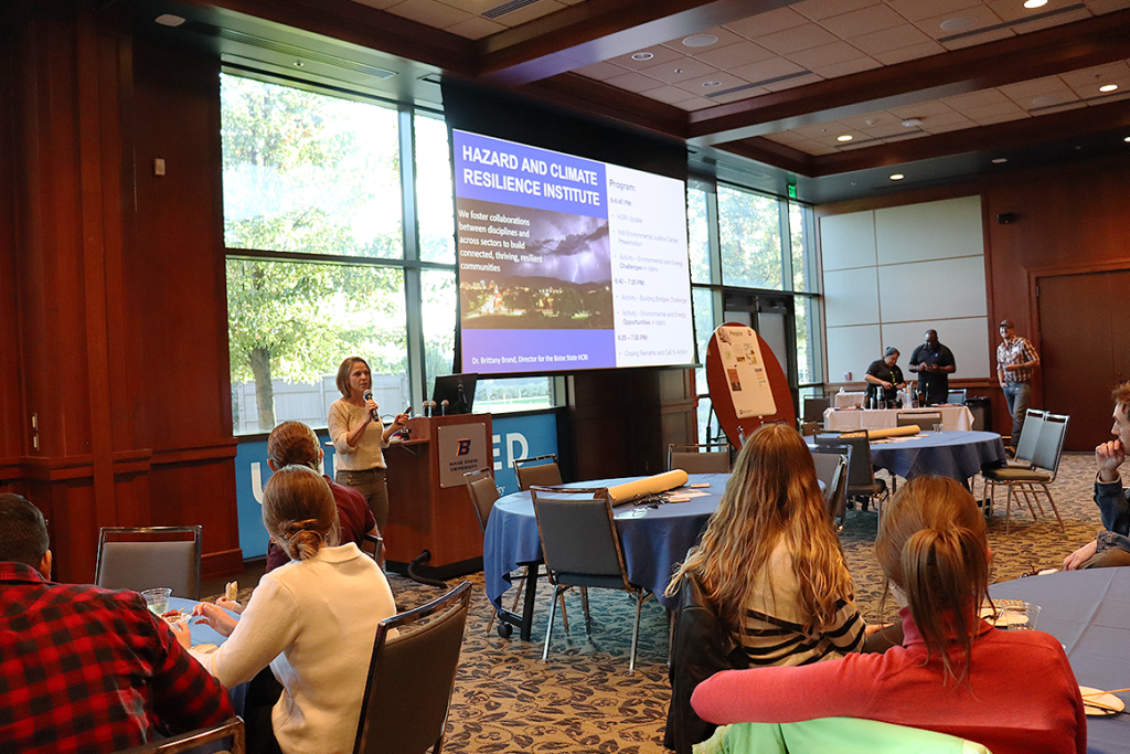 Brittany Brand giving a speech in front of attendees at the HCRI Networking Event, Building Bridges.