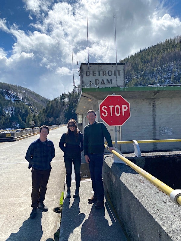 Three people stand near stop sign on the Detroit Dam