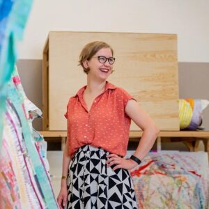 Astri Snodgrass smiles beside her artwork