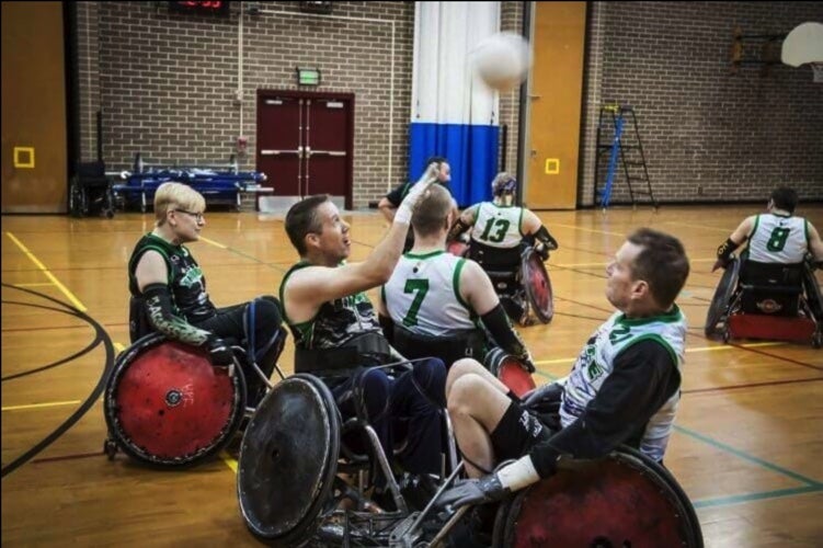 A room full of people in wheelchairs playing wheelchair basketball.