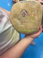 A student's rock that has the words "Be Kind" and two people drawn on it.