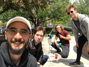 Four people posing with a completed handmade windmill