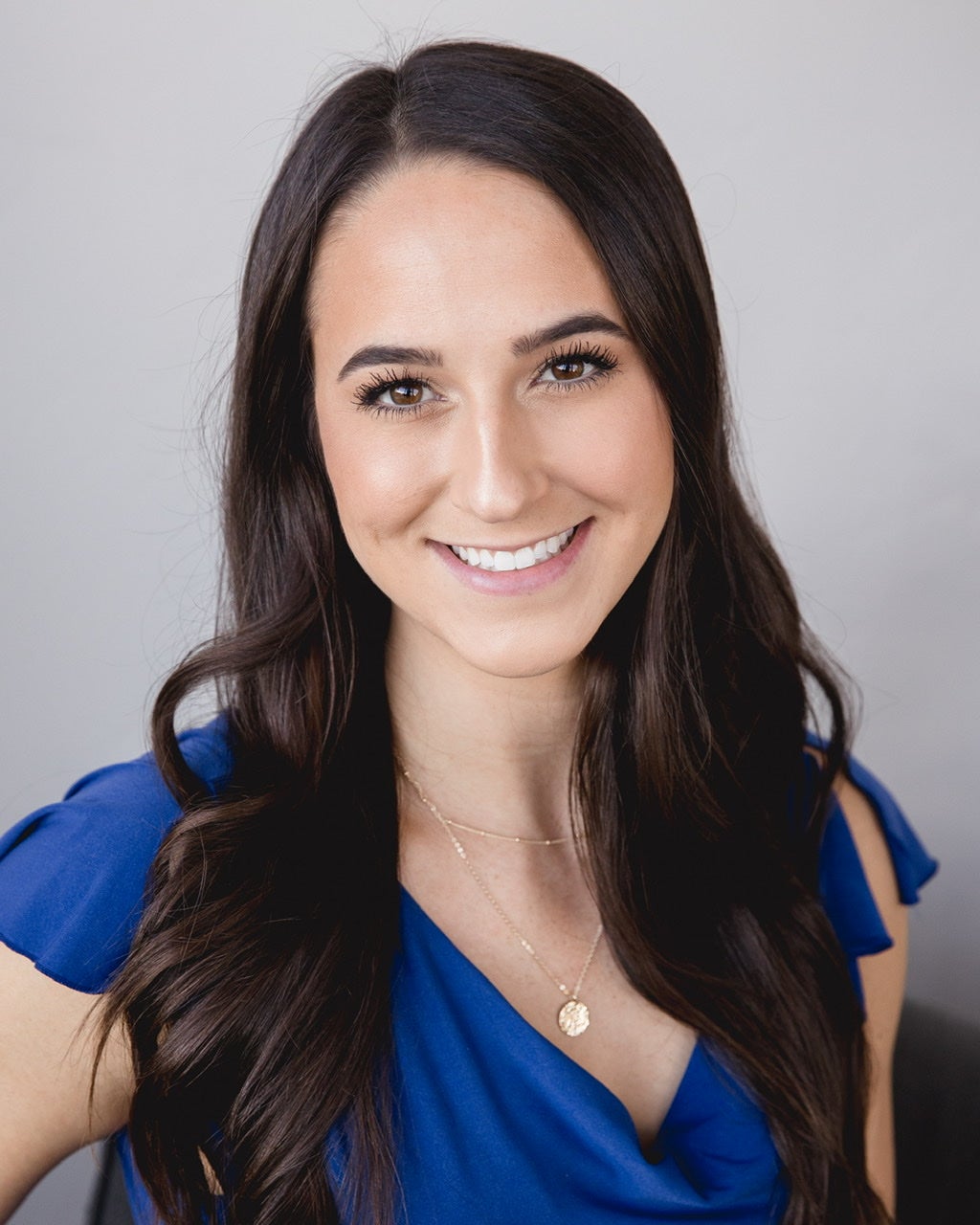 A photo of the interviewee--she has light skin, brown hair, and brown eyes. She is smiling and wearing a blue top.