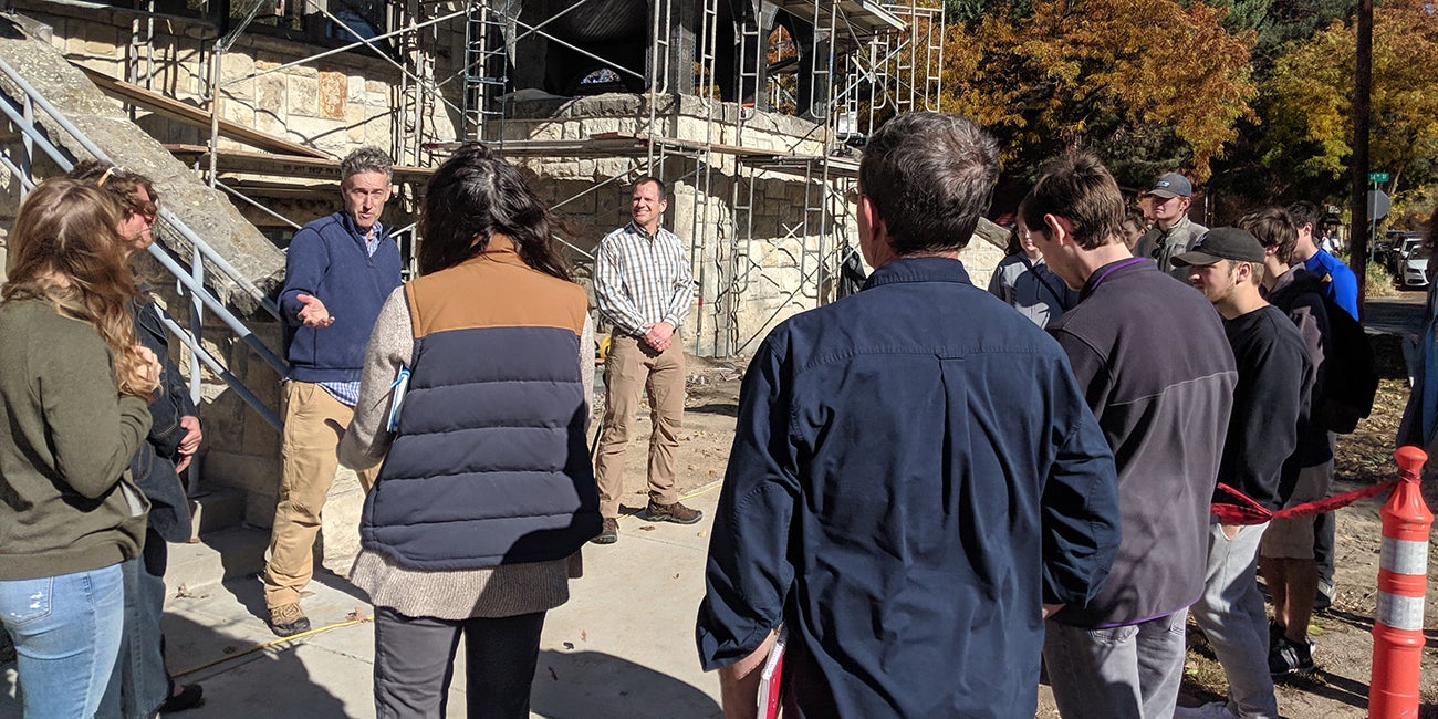 Group of people stand outside a building with a scaffold