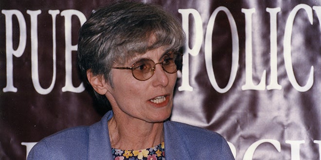 Image of Shuler with sign behind her saying public policy