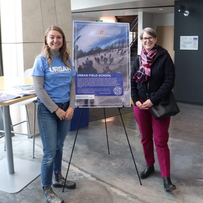 SPS faculty members pose with a poster about their program