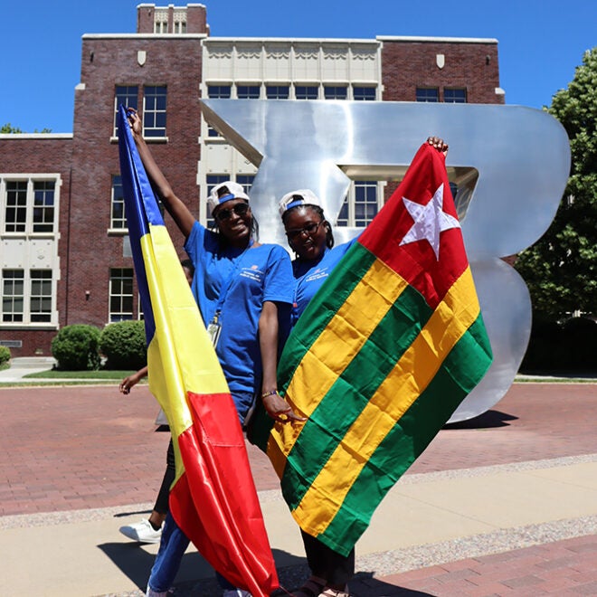 Mandela Washington Fellows pose with African flags in front of the Boise State B sign