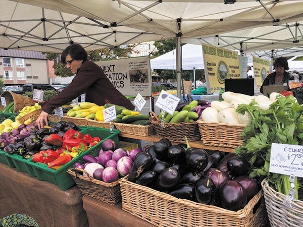 A farmers market stand with lots of produce. 