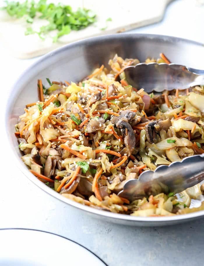 Egg roll in a bowl with mushrooms and shredded carrots.