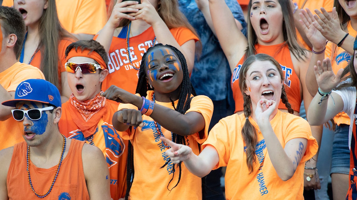 Students wearing Bronco gear and cheering at a game