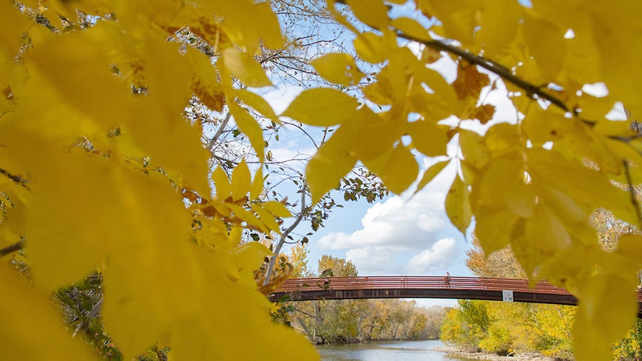 Autumn view of a red pedestrian bridge crossing a river 