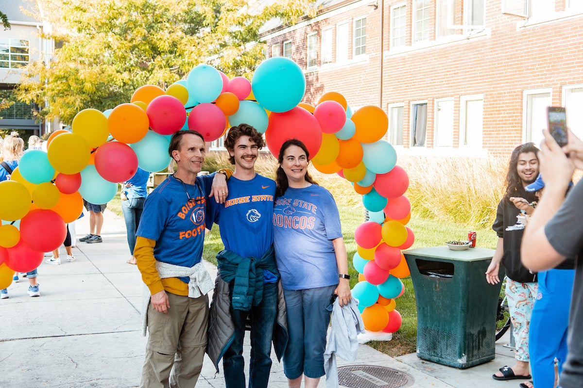 Student and parents pose for a picture under balloon arch