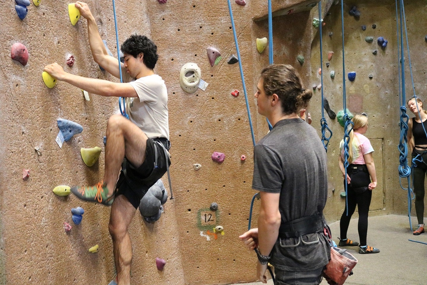 Zack works with a climbing student.