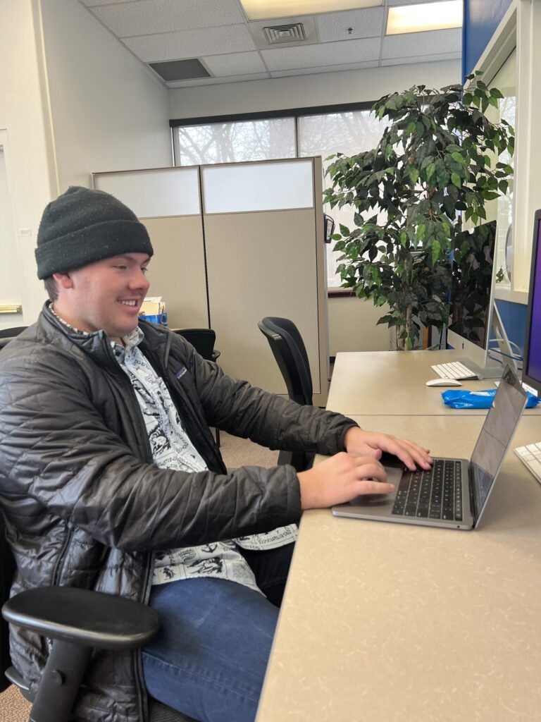 Ryan Dougherty sitting at a desk typing on a laptop