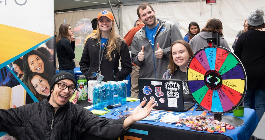 Students post at a table with a prize wheel