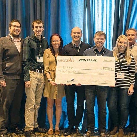 Lumineye challenge participants hold a large check.