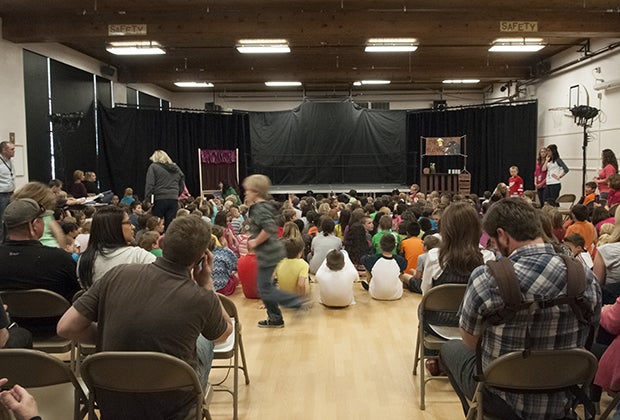 back of room where people are sitting waiting for play to start. Stage is set up but empty.