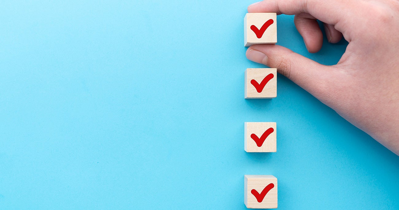 Hand placing checkmark blocks in a vertical line