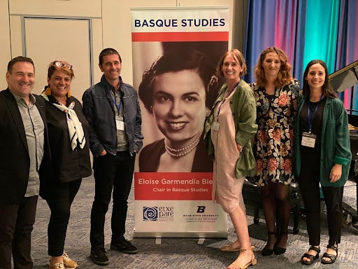 People stand around a Basque studies banner with an image of Eloise Garmendia Bieter