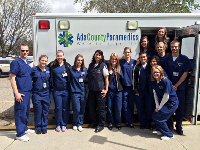 Students pose with EMT in front of ambulance