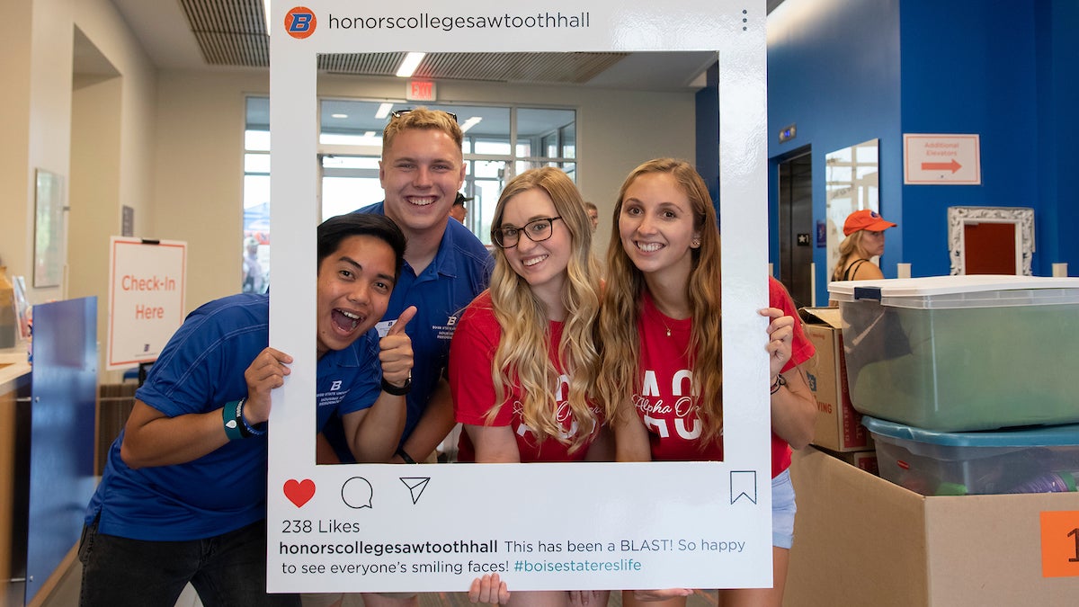 Students hold oversize Instagram frame for Honors College Sawtooth Hall. 