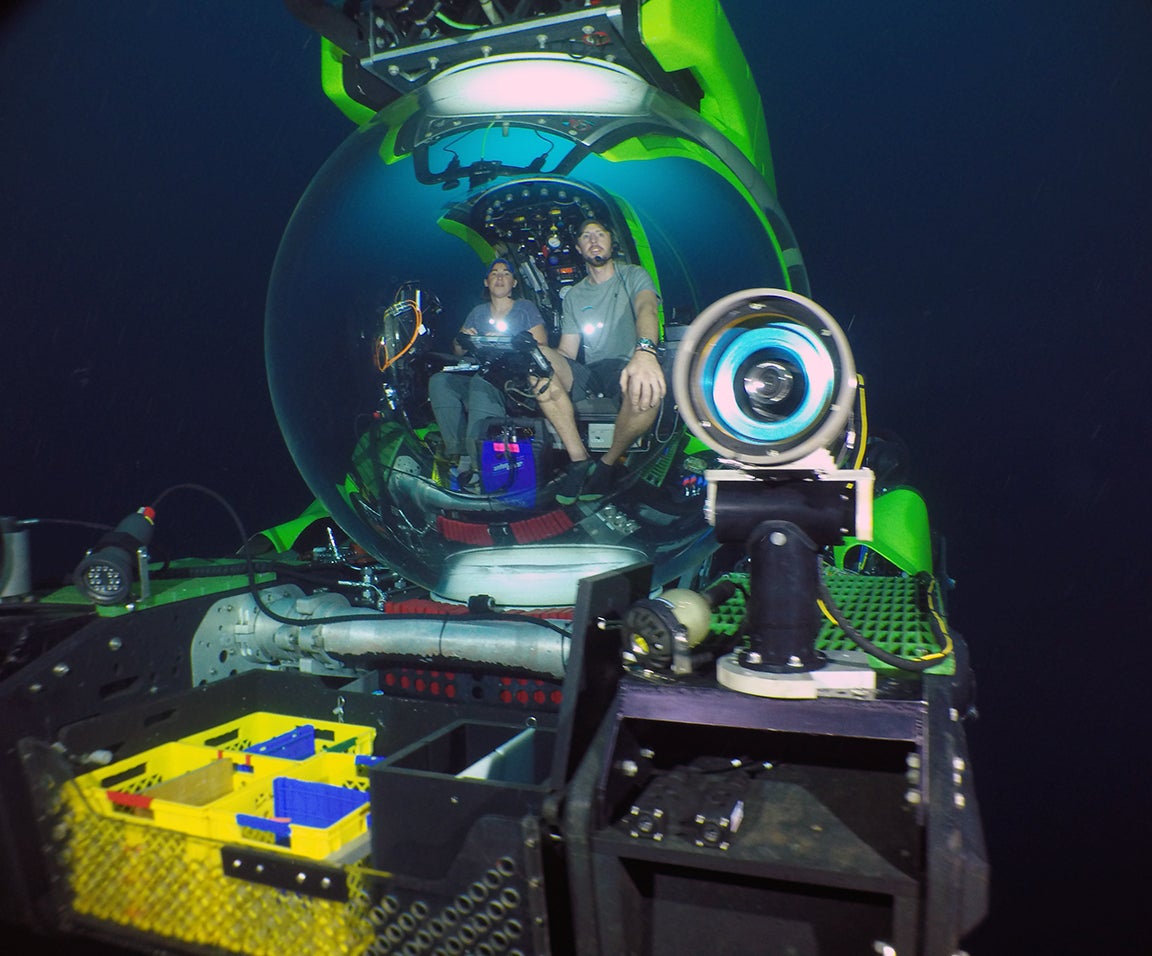 two individuals sit in submerged research submarine