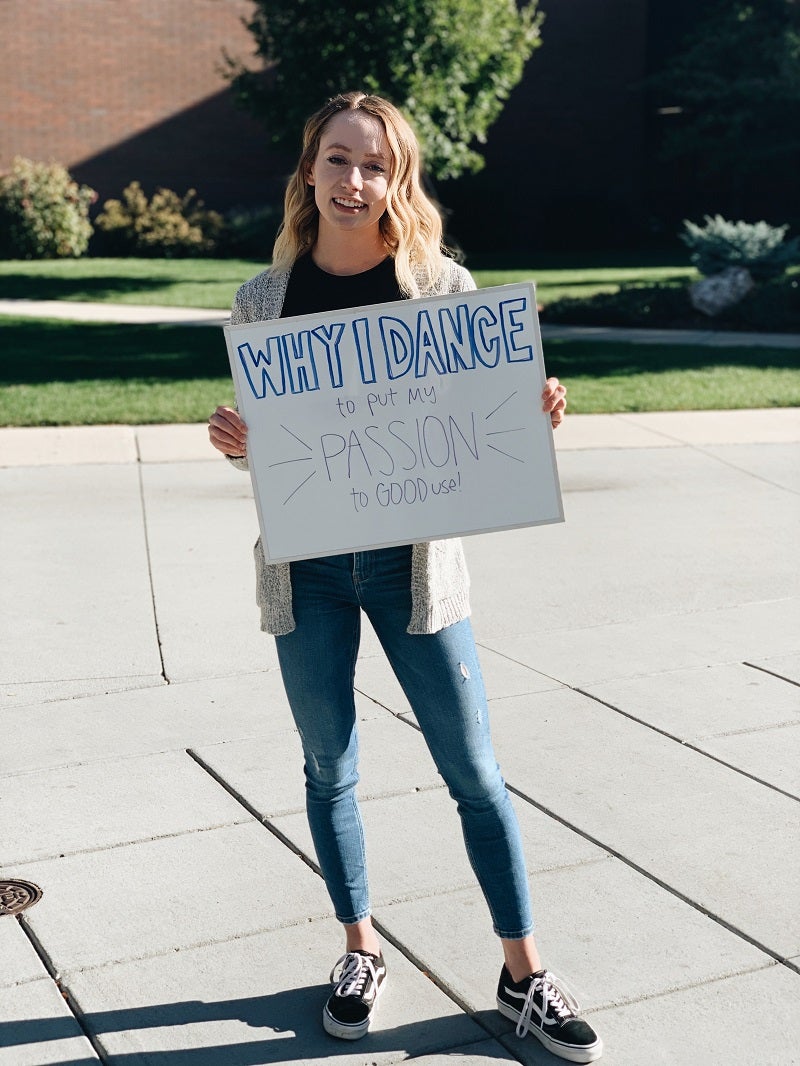 A dancer holds up a sign that says, why I dance to put my passion to good use.