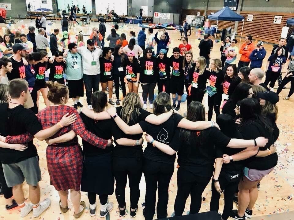 A large group circle up arm and arm together.