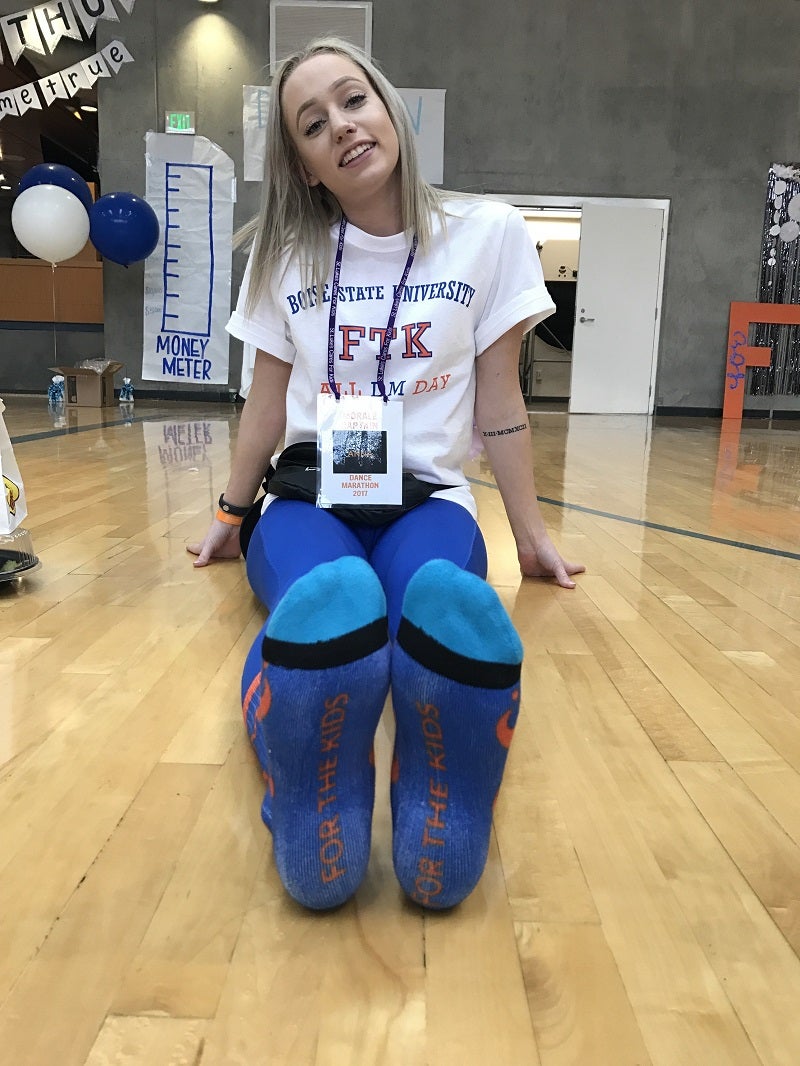A dancer sits on a gymnasium floor.