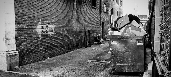 alley with a dumpster overflowing with cardboard