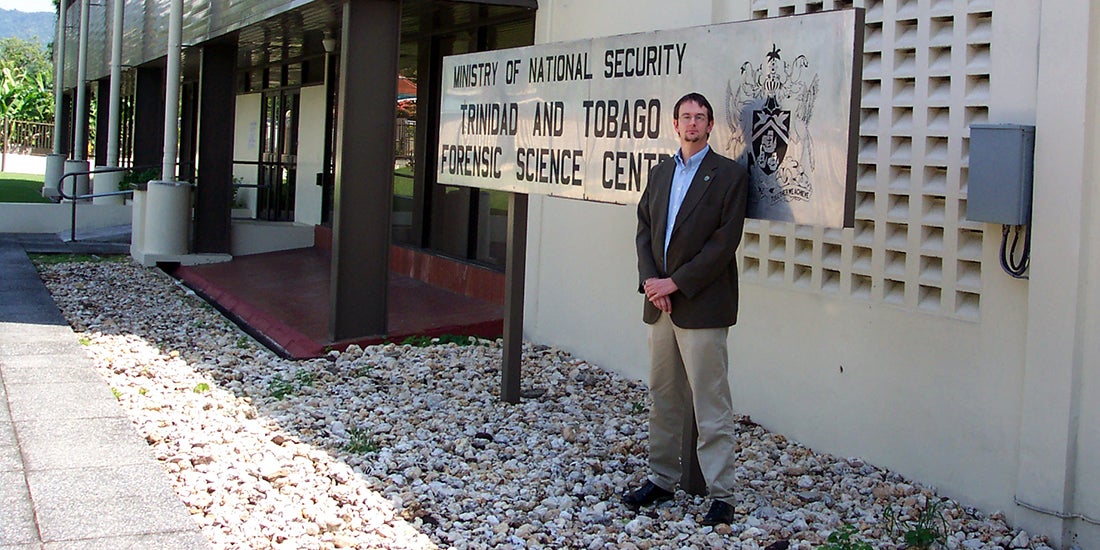 Bill King stands in front of the Ministry of National Security Trinidad and Tobago Forensic Science Centre sign.