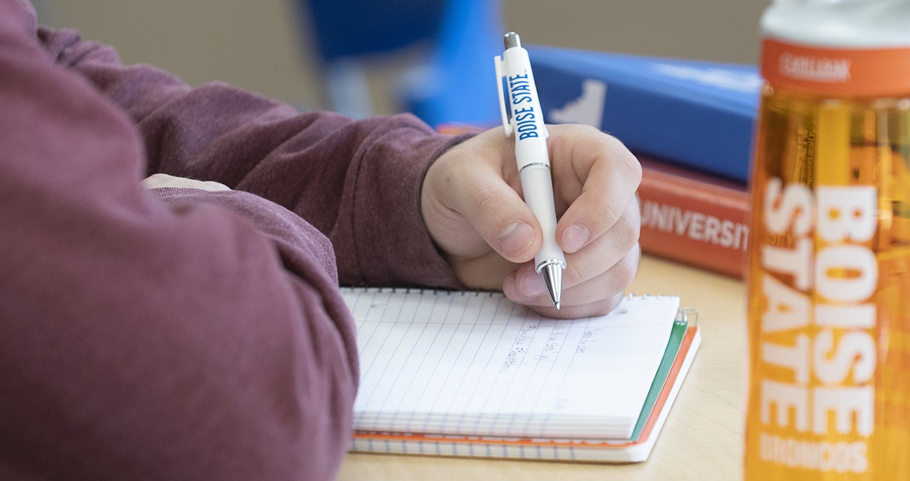 Student writes in a notebook with a pen